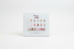 A Perma Color nail polish display card showing 12 different shade options for press-on nails, arranged in rows of three with circular swatches above and elongated nail color samples below on a white card.