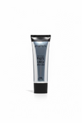 A tube of Smashbox Photo Finish Primer stands on a glass display counter in a retail store. The silver tube with black caps is centered in front of a laptop, with shelves of other products visible in the background.