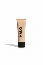 A tube of HAO Hair Health Hairglow All Purpose Moisturizer standing on a glass display counter inside a retail store. The background shows shelves with products, a laptop, and store fixtures.