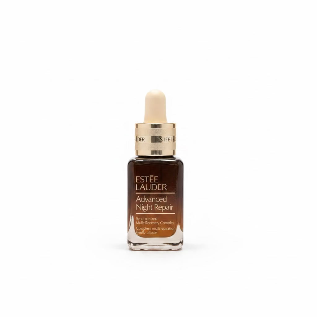 Estée Lauder Advanced Night Repair serum in a dark brown glass dropper bottle with gold accents, displayed on a glass counter in a retail store with a laptop in the background.