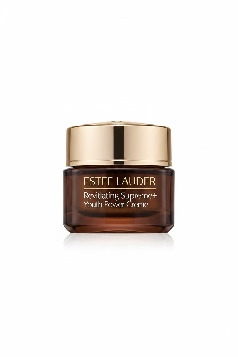 A hand holding an Estée Lauder Revitalizing Super Cream jar, showing the gold and clear packaging against a background of clothing and storage items.