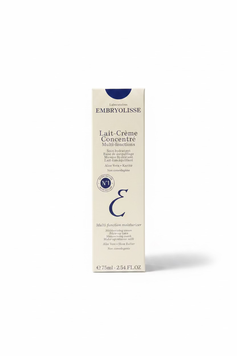 A person holds a box of EMBRYOLISSE Lait-Crème Concentre Multi-functions moisturizer in a retail store setting with a glass display counter and shelves in the background.