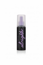 Urban Decay All Nighter foundation bottle with a black body and frosted cap, displayed on a glass counter in a retail store.