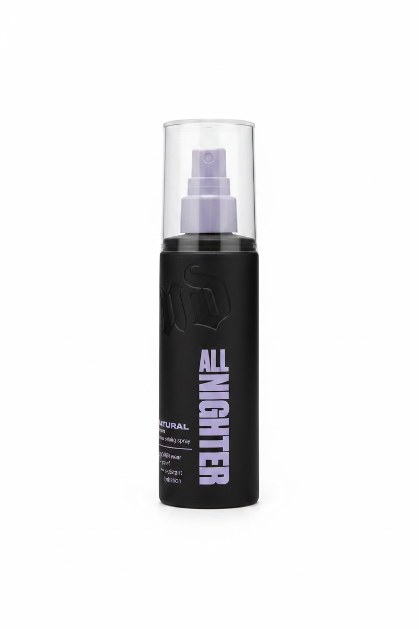 A black cylindrical hair product bottle labeled 'ALL NIGHTGLITTER' with a silver spray top, standing on a glass counter in a retail store. A laptop, packaging boxes, and a person's hand are visible in the background.