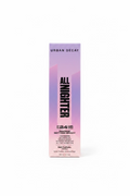 A box of Urban Decay All Nighter Makeup Setting Spray standing on a glass display counter in a retail store. The packaging is a soft pink-to-lavender gradient with bold black text.