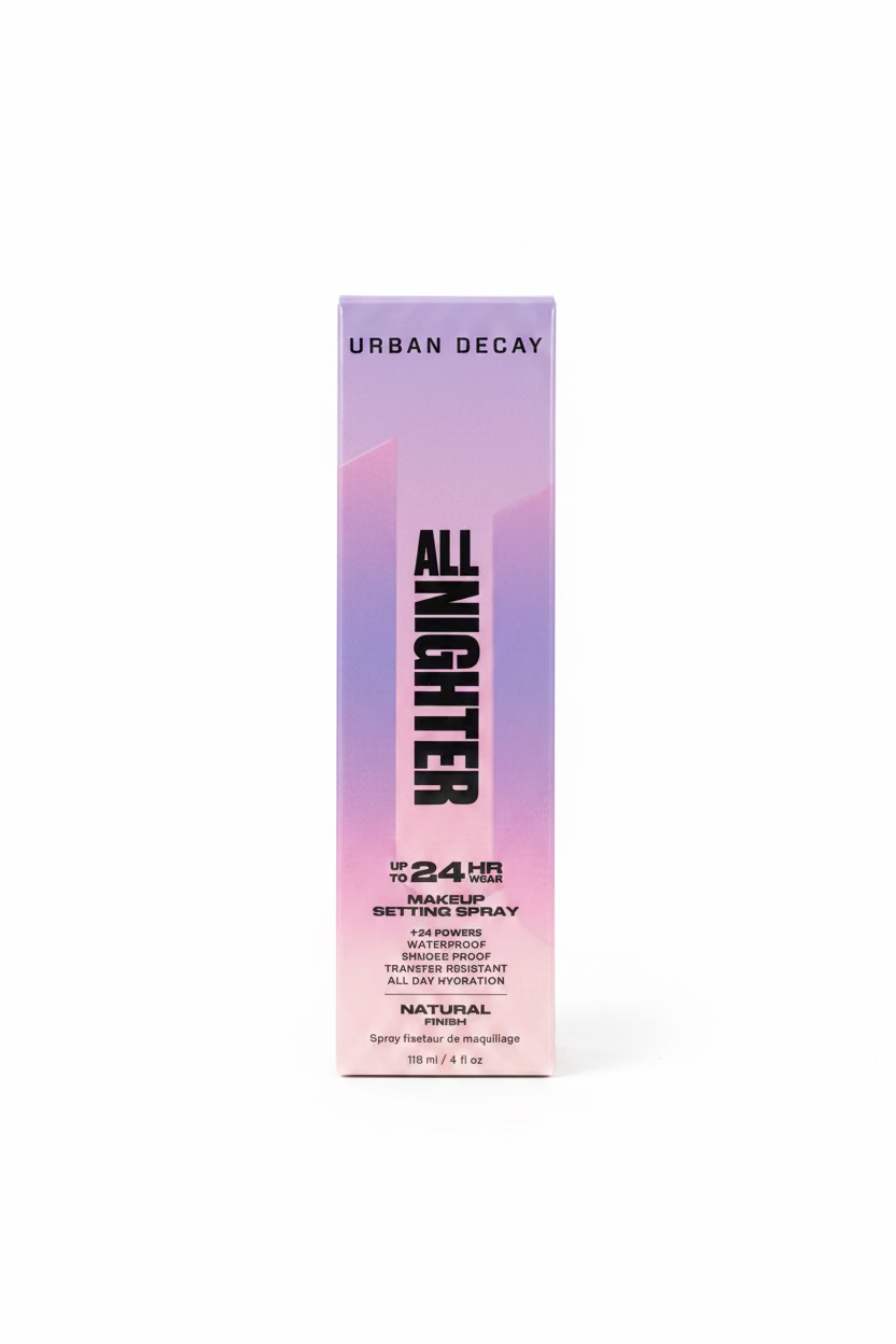 A box of Urban Decay All Nighter Makeup Setting Spray standing on a glass display counter in a retail store. The packaging is a soft pink-to-lavender gradient with bold black text.