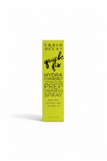 A yellow box of Urban Decay Quick Fix Hydra Charged Prep Priming Spray stands on a glass display counter in a retail store. Winston and Mynk boxes are visible in the background, along with a laptop and other cosmetics.