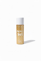 A bottle of Anastasia Beverly Hills Dewy Set Setting Spray, featuring a gold glitter bottle and a white cap, displayed on a glass shelf in a retail environment.