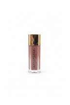 Anastasia Beverly Hills Liquid Blush in a clear rectangular bottle with a metallic gold cap, displayed on a glass shelf next to a silver Apple laptop.