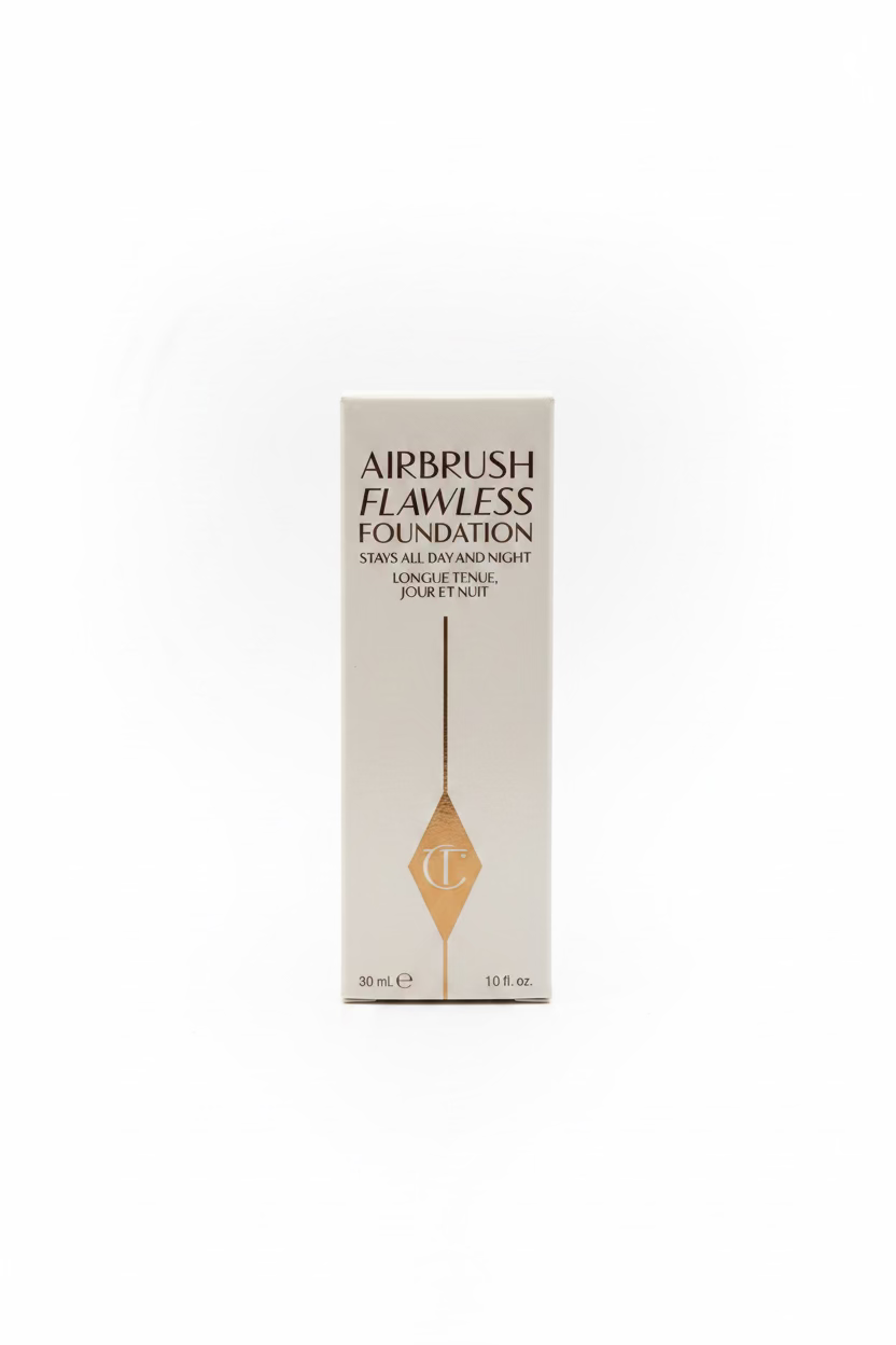 A box of Charlotte Tilbury Airbrush Flawless Foundation, 30 ml, standing upright on a glass counter with other cosmetic boxes in the background.