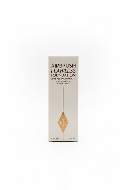 A box of Charlotte Tilbury Airbrush Flawless Foundation, 30 ml, standing upright on a glass counter with other cosmetic boxes in the background.
