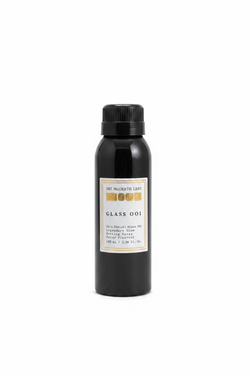 A black cylindrical bottle of Pat McGrath Labs Class 001 Skin Fetish Glass Oil setting spray, displayed on a glass shelf with Medcube skincare boxes in the background.