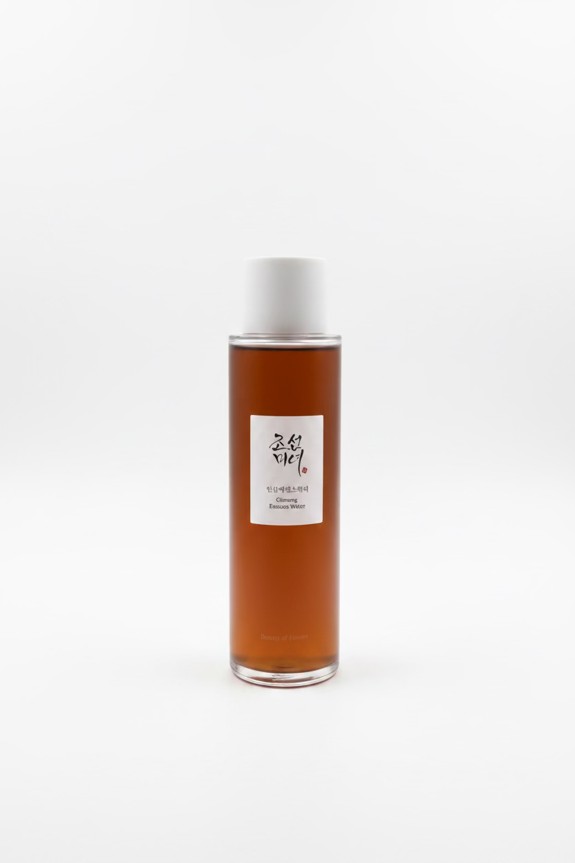 A bottle of Medicube Essence Water in a brown amber bottle with a white cap, displayed on a glass shelf alongside its white and peach packaging boxes.