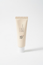 A beige cosmetic tube labeled 'Beauty of Joseon' and 'Probiotics SPF 30+' stands on a reflective glass counter in a retail setting, with product boxes and shelves visible in the background.