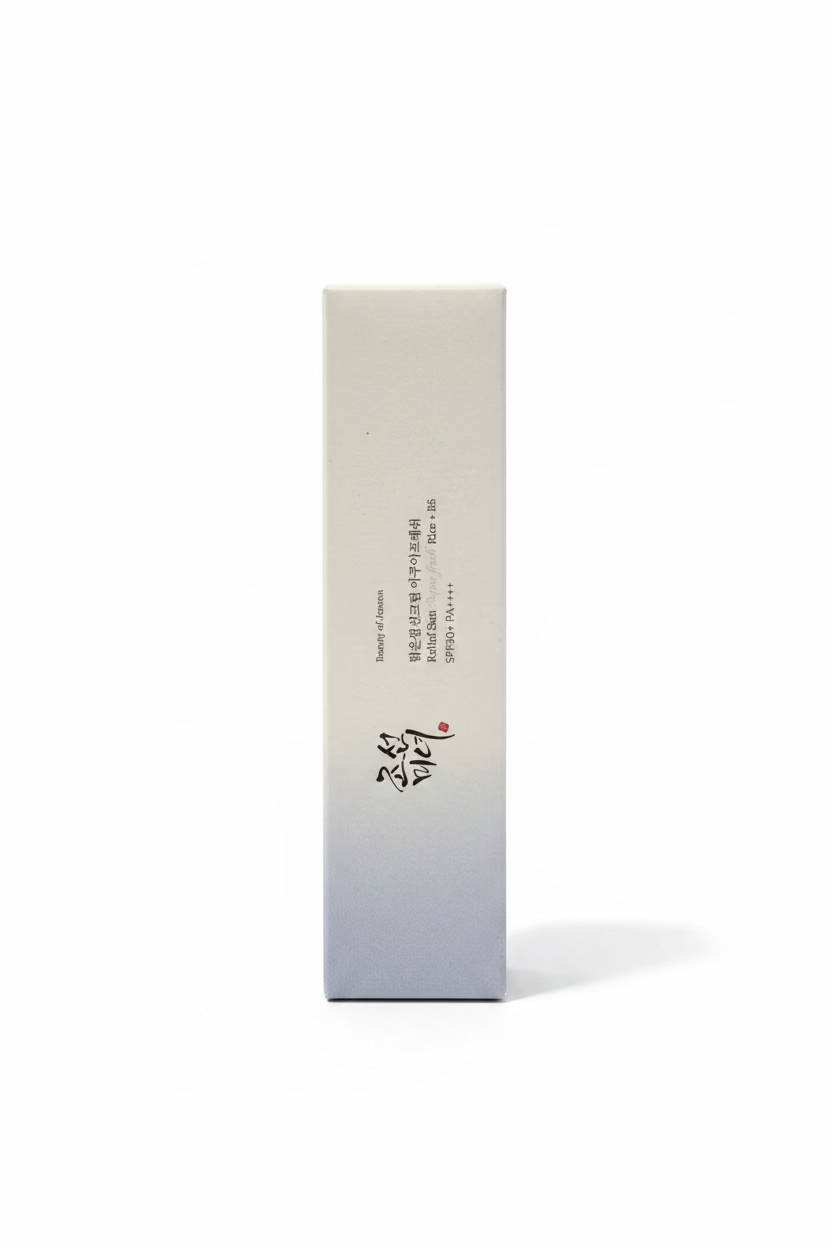 A tall white rectangular box with Korean text stands on a glass display counter in a retail store. A blue cosmetic tube is partially visible to the right, and other store fixtures and products appear blurred in the background.