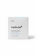 A white box of medicube Zero Pore Pad Mild skincare pads, placed on a glass display counter in a retail store with a laptop and shelves visible in the background.
