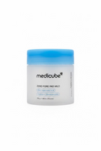 A jar of medicube Zero Pore Pad Mild skincare pads, featuring a frosted white container and a bright blue lid, displayed on a glass shelf in a retail setting.