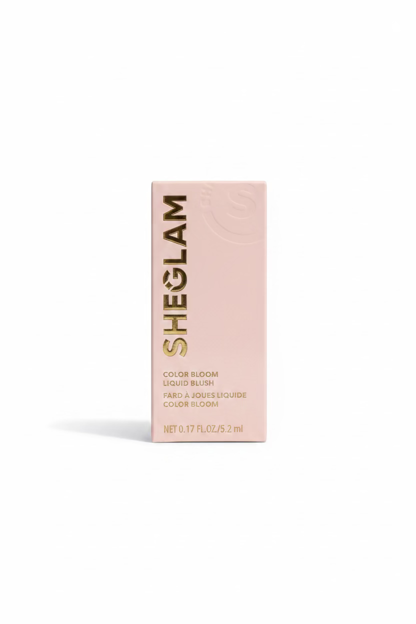 A pink SHEGLAM Color Bloom liquid blush box standing on a glass display counter in a retail store. The SHEGLAM brand name is printed vertically in black on the front of the box, with additional product text below.