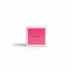 A hand holding a small square pink box with the words 'On Point' printed on the front, set against a background of blue denim clothing.