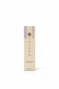 A tall, narrow beige box for Tatcha Luminous Dewy Skin Mist stands on a glass display counter inside a retail store. The box features the Tatcha logo and name vertically printed in black, with a decorative blue and white patterned stripe on the right side.