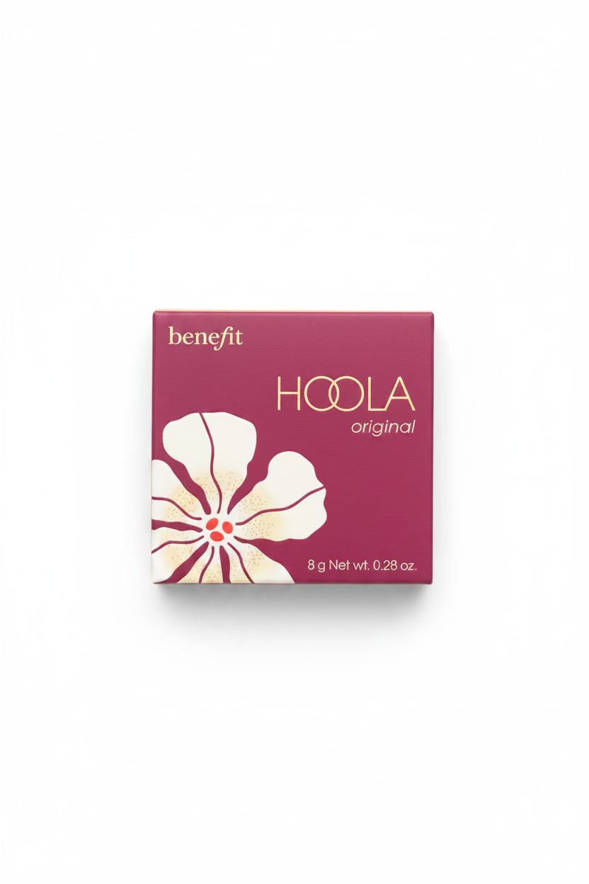 A hand holding a Benefit Hoola Original makeup compact in its original magenta packaging, with a hibiscus flower graphic on the front.