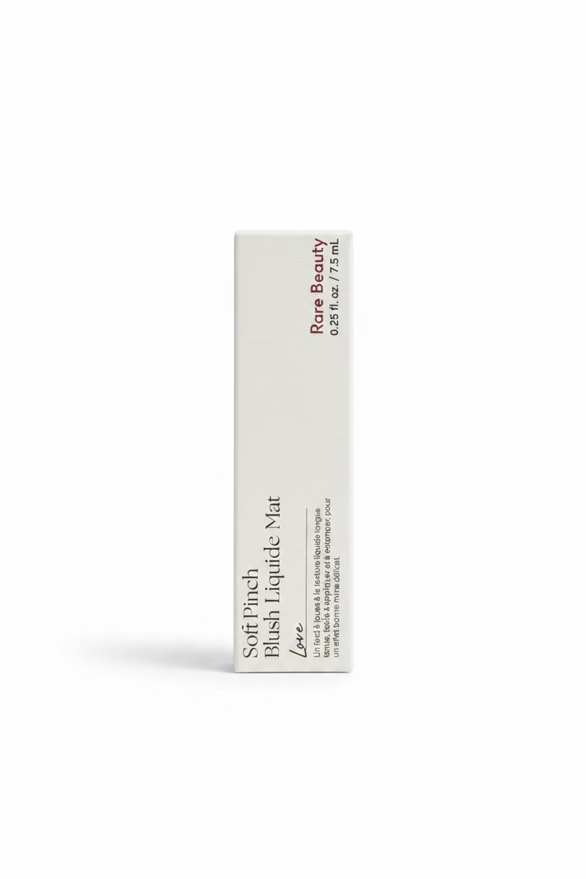 A hand holding a white rectangular box of Rare Beauty Soft Pinch Blush Lévée Love blush in a retail store setting.