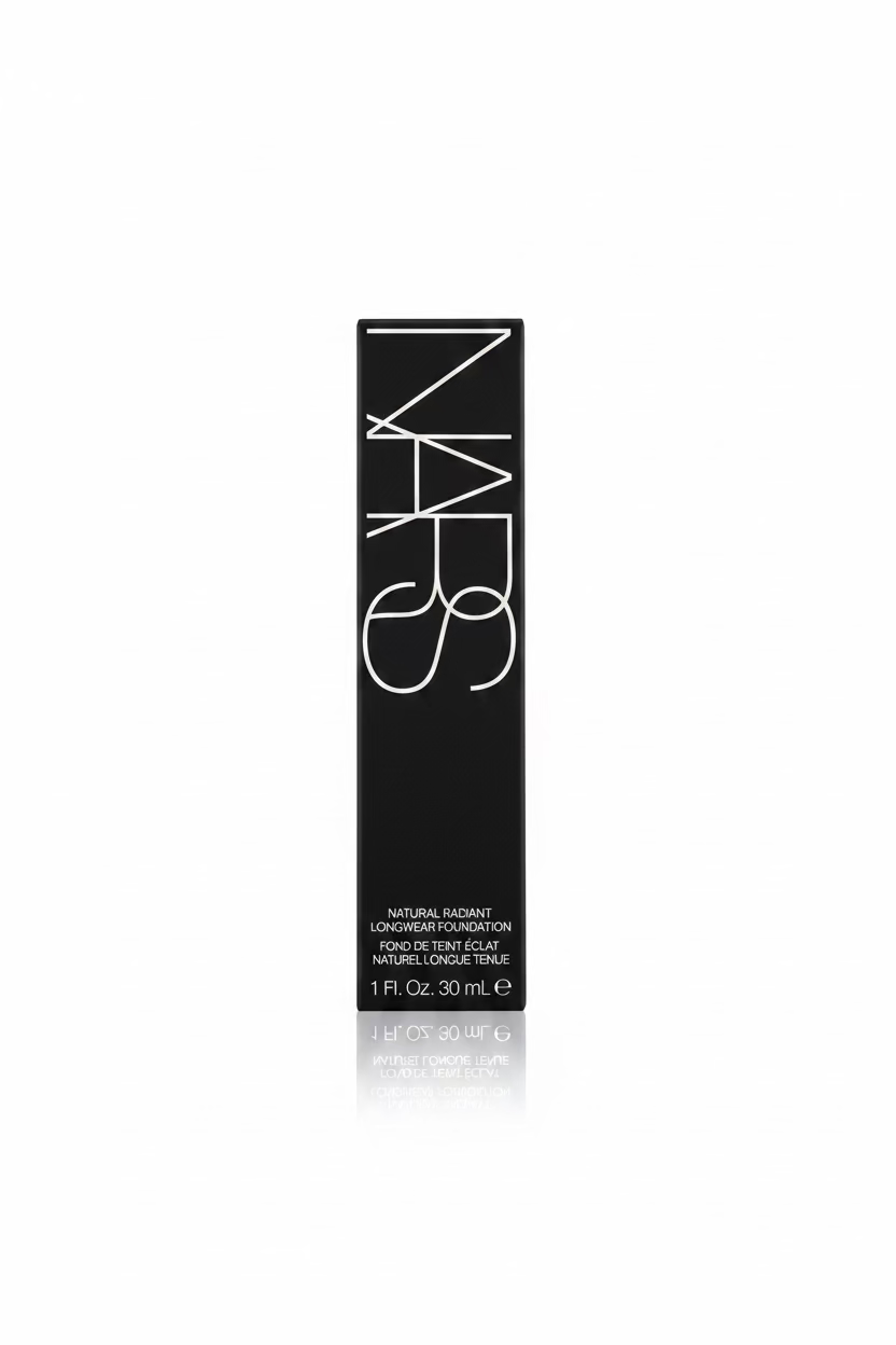 A hand holding a single NARS Natural Radiant Longwear Foundation tube in its original black packaging, with a beige shirt and a store shelf in the background.