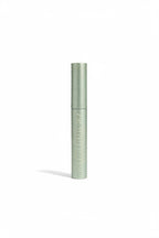 A close-up of a makeup pencil with a metallic olive green barrel and a dark gray tip, resting on top of an open laptop in a retail setting.