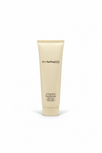 A tube of MAC Hyper Real Fresh Convex Cleanser standing on a glass counter inside a retail store, with a laptop and shelves of cosmetics in the background.