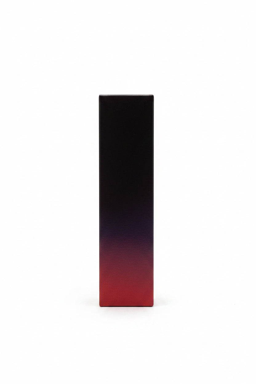 A tall rectangular product box with a dark gradient design stands upright on a white surface next to an open laptop. The background shows shelves with colorful boxes and items in a retail or office setting.