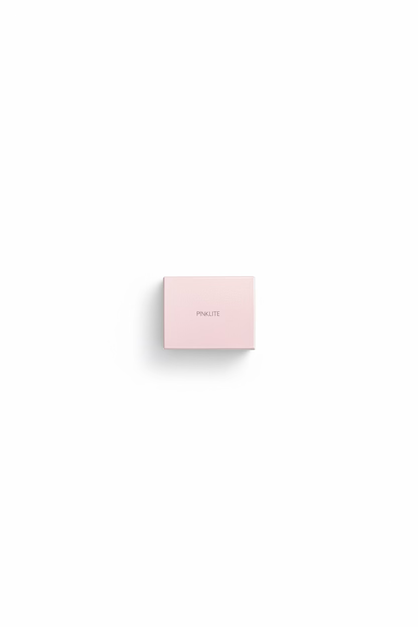 A hand holding a small pink box labeled 'PINKLITE' in a casual indoor setting with a person's legs and clothing visible in the background.