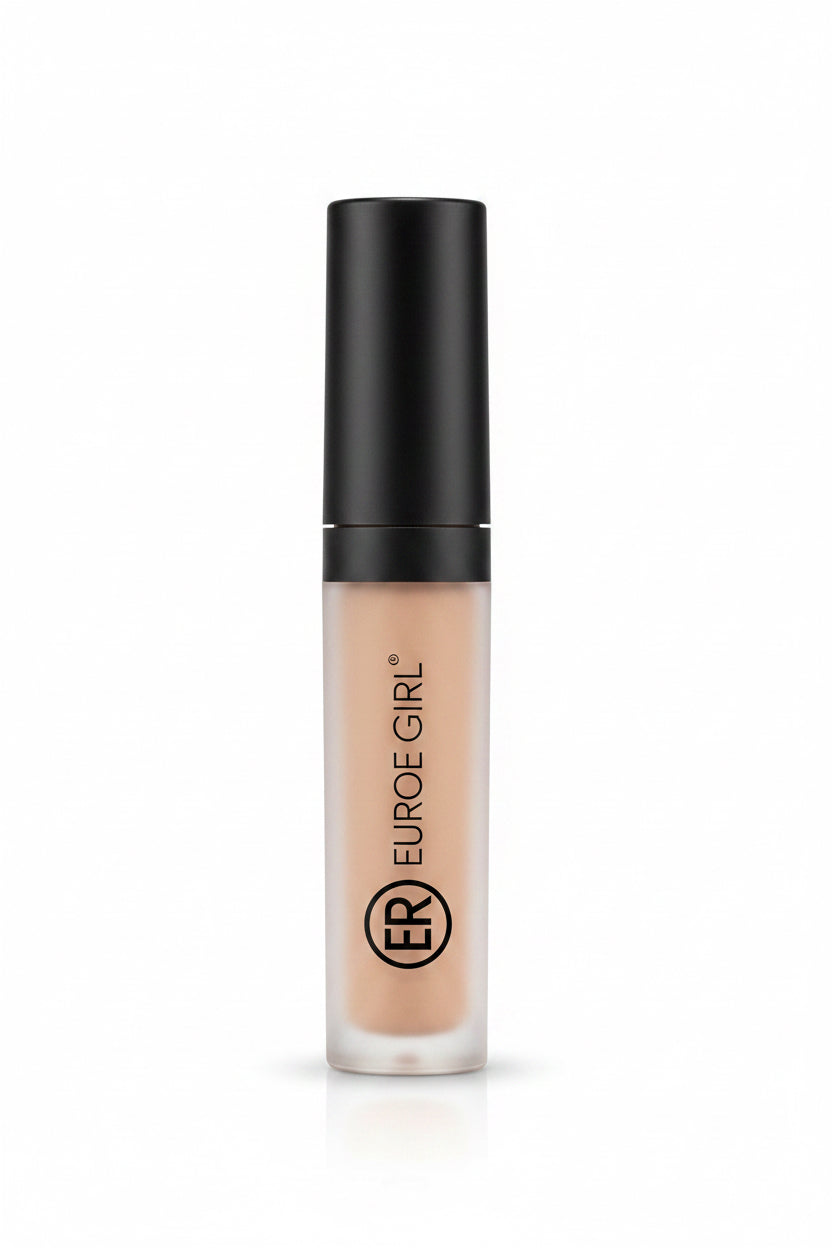 A hand holding a bottle of Euro-Jaune Gels concealer, showing the beige liquid inside a frosted bottle with a black cap, set against a cluttered indoor background.