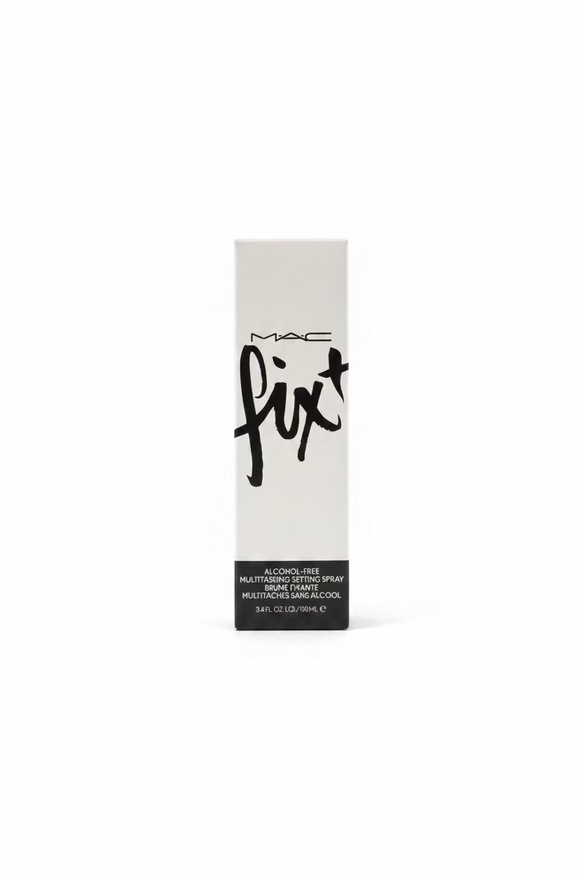 A boxed MAC Fix + Alcohol-Free Multistrating Styling Spray stands on a glass display counter in a retail cosmetics store. The tall white box has black MAC branding and large 'fix+' script.