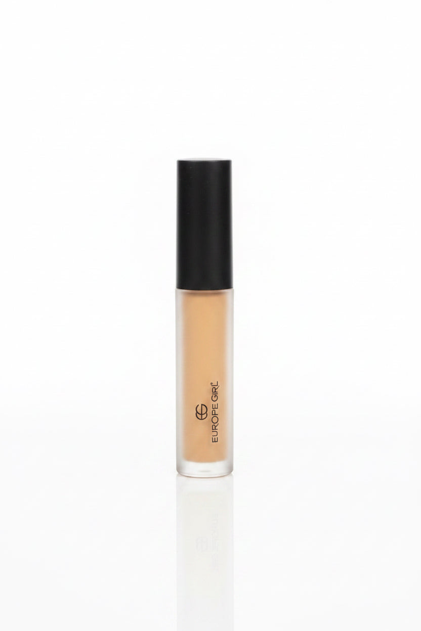 A hand holding a tube of BB Grade Gel foundation, showing the beige liquid makeup inside a frosted bottle with a black cap, set against a cluttered indoor background.