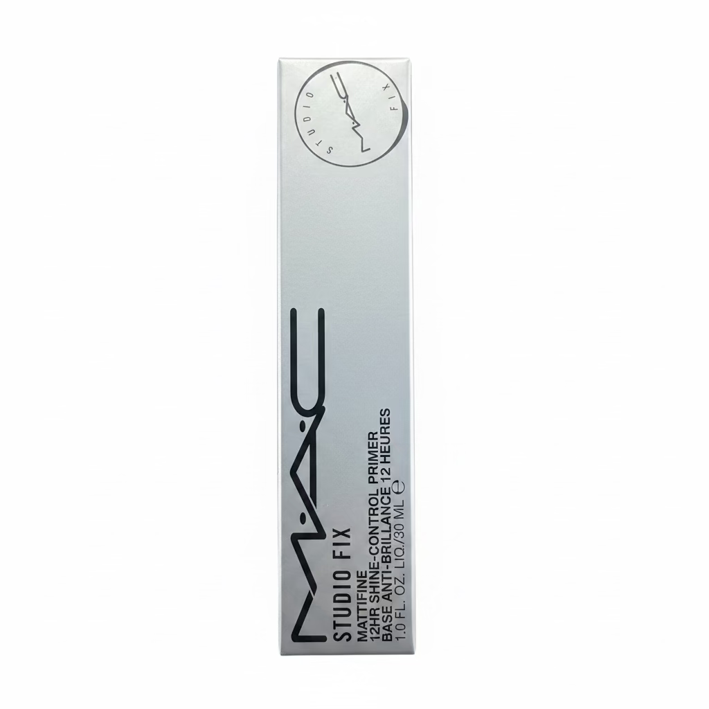 A hand holding a white box of MAC Studio Fix 24 Hour Face Control Primer, with a cluttered desk and books in the background.