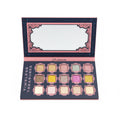 A makeup palette labeled 'TIMELESS TREASURES' held open in a store setting. The palette has 16 square pans in various glitter and matte shades of pink, gold, silver, and white, set against a dark background with pink ornate borders.