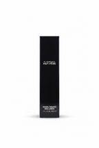 A black rectangular box of MAC Prep+Prime Natural Radiance Base Luminére, standing on a glass display counter inside a retail store.