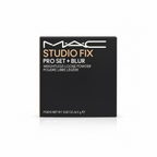 A hand holding a black MAC Studio Fix Pro Set + Blur loose powder compact box, with a cluttered background of books and other makeup items.