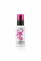 A bottle of MAC Fix Stay Over Alcohol Free Long Lasting Makeup Remover is displayed on a glass counter in a retail setting, with a laptop, scissors, and other cosmetic packaging in the background.