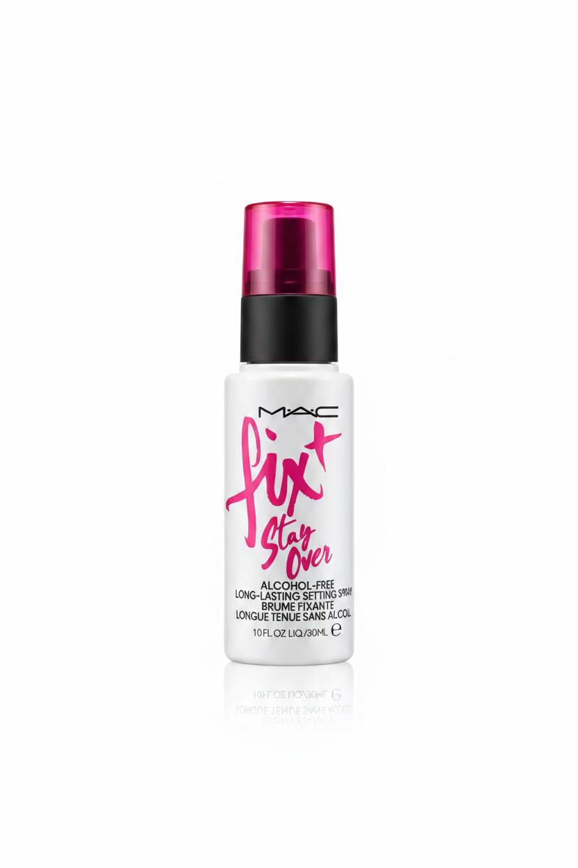 A bottle of MAC Fix Stay Over Alcohol Free Long Lasting Makeup Remover is displayed on a glass counter in a retail setting, with a laptop, scissors, and other cosmetic packaging in the background.