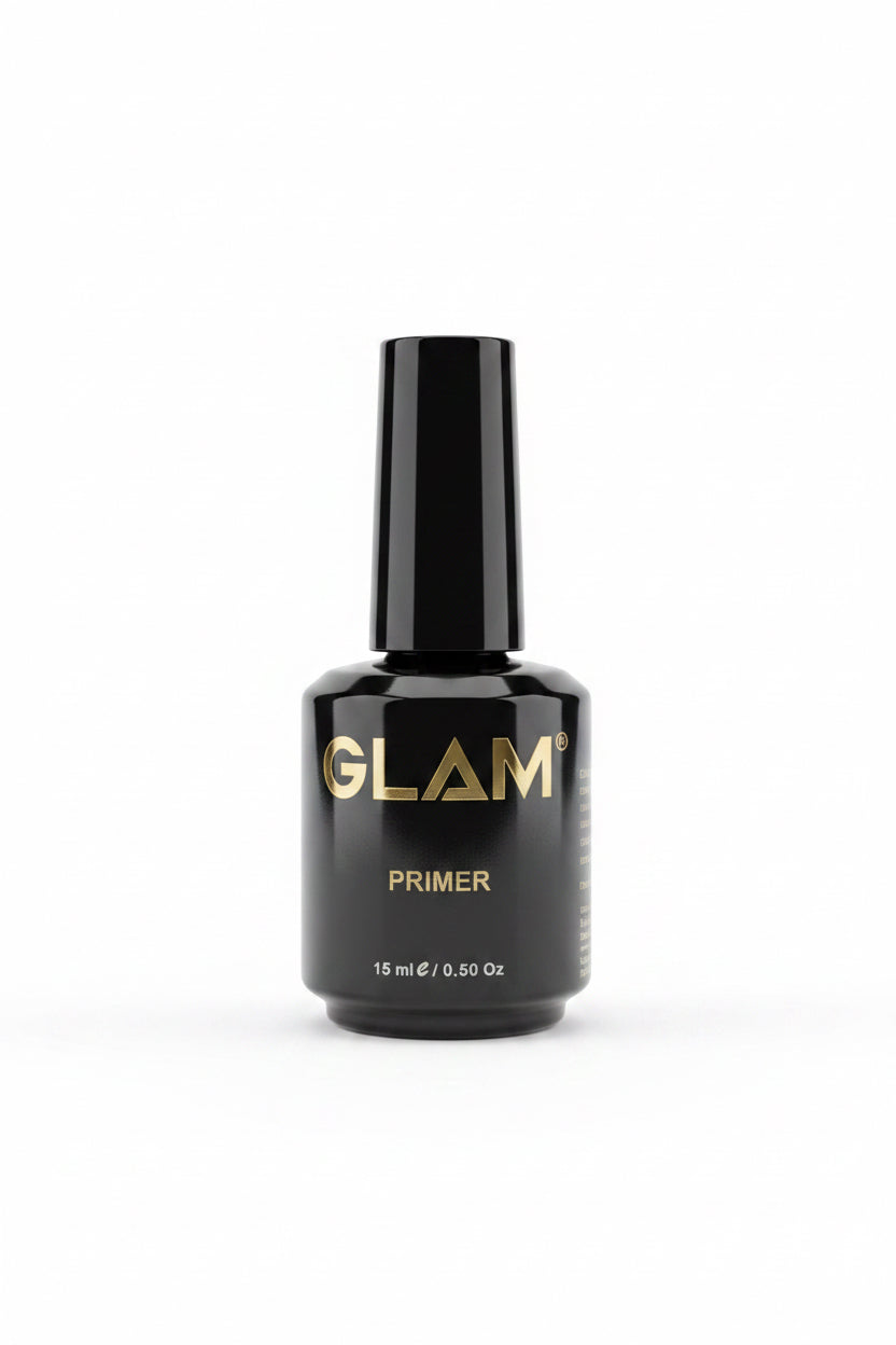 A black bottle of GLAM PRIMER 15 ml cosmetic product placed on top of an open silver laptop, with two more bottles in the background on a desk.