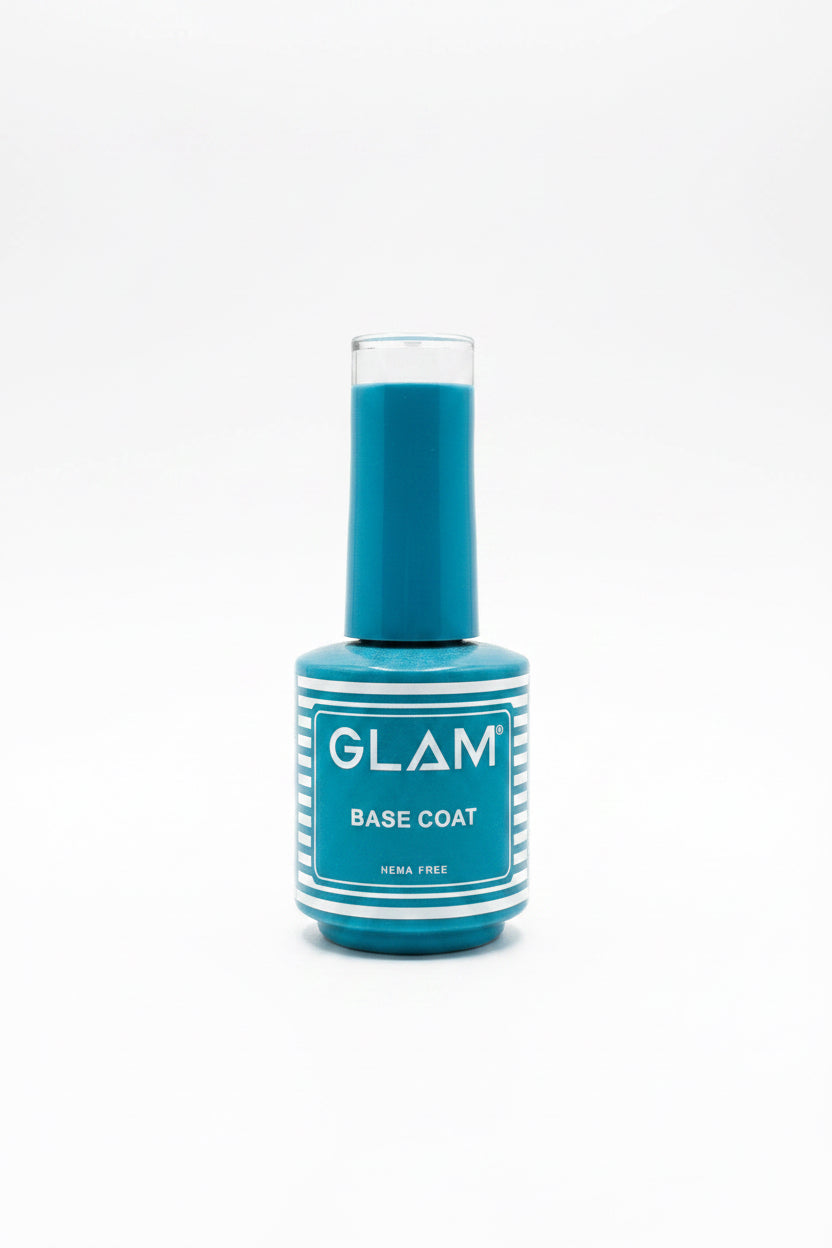 A bottle of GLAM Base Coat nail polish in a teal-blue shade, placed on top of an open silver laptop in an office setting with other bottles in the background.