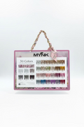 A hand holds a pink MYNK nail color display board featuring 30 faux nail tips in various shades, with a gold chain handle and a pink bow. The background shows a nail salon counter with more nail polish bottles.