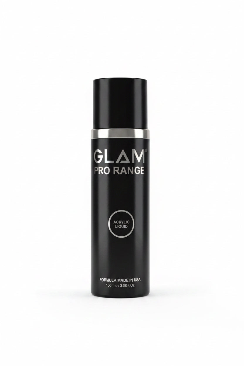 A black Glam Pro Range acrylic liquid bottle wrapped in clear plastic, standing on a desk next to an open laptop in an office setting.