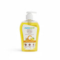 A bottle of Mama Earth Vitamin C Daily Glow Face Wash with a white pump dispenser, filled with yellow liquid, placed on a black counter next to a green basket containing other skincare products.
