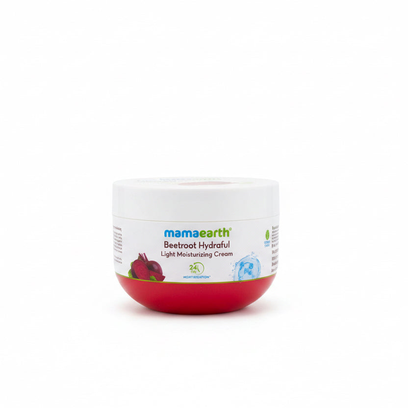 A jar of Mamaearth Beetroot Hydraful Light Moisturizing Cream placed on a dark tabletop in front of a mint green plastic basket, with a laptop partially visible on the right.