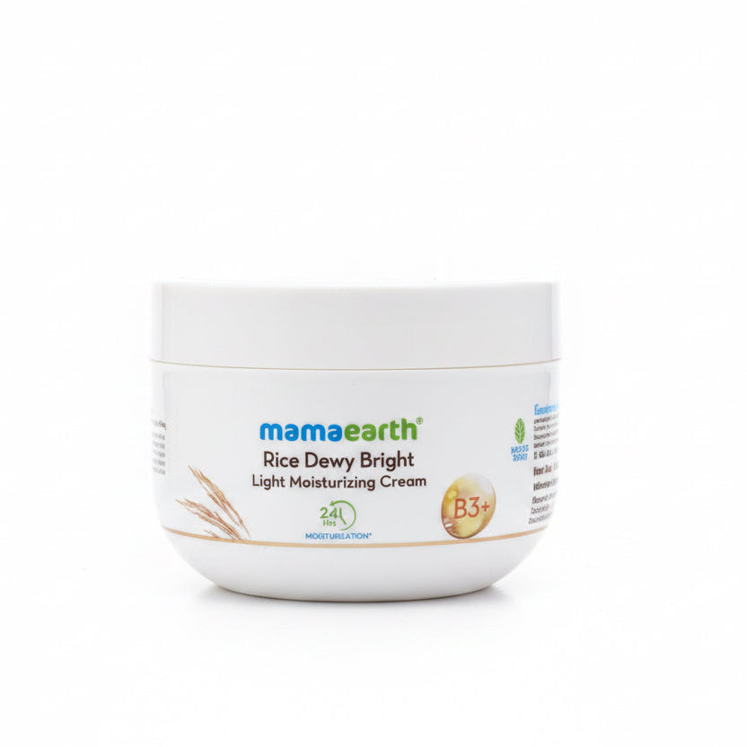 A white jar of Mama Earth Rice Dewy Bright Light Moisturizing Cream placed on a dark surface, with a green plastic basket and a light-colored wall in the background.