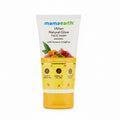 A tube of Mama Earth Ubtan Natural Glow Face Wash standing on a desk in front of an open laptop, with a calculator and a blurred person in the background.