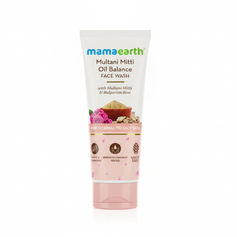 A tube of Mama Earth Multani Mitti Oil Balance Face Wash is displayed on a black countertop. The background features a green plastic basket, a laptop on a red wallet, and a store interior with shelves.