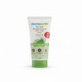 A tube of Mamaearth Tea Tree Pimple Control Face Wash standing on a laptop keyboard in an office setting, with a desk, chair, and keyboard visible in the background.